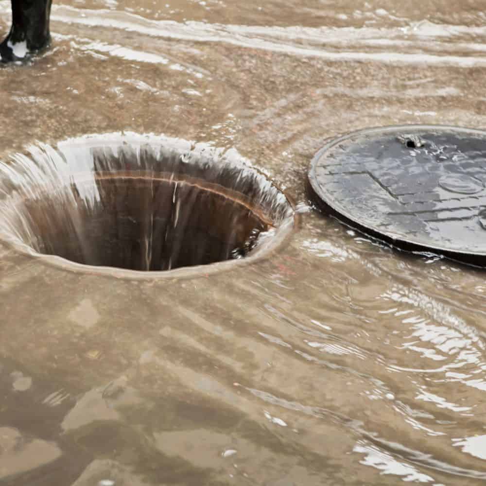 Flooded drain cover with water overflow, drainage repair service. Soakaways Swindon Wiltshire Experts